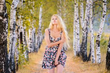 An attractive girl with long hair in a short dress walks in the Park.