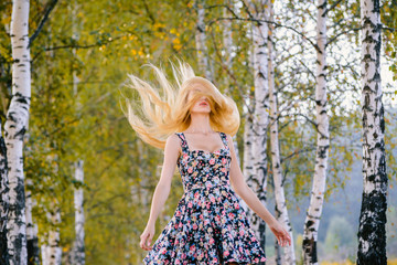 An attractive girl with fluttering hair and a short dress walks in the Park.