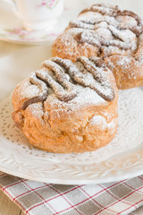 Choux buns filled with cream and drizzled with chocolate and icing sugar