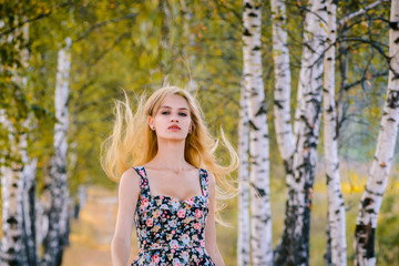 An attractive girl with fluttering hair and a short dress walks in the Park.