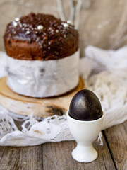 Amazing Chocolate Easter Cake with chocolate drops and dry cherries on an old wooden background with black and golden eggs. Easter concept. Selective focus, close up, copy space.