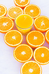 Halved oranges fruit and glass of juice. Citrus for making juice. A lot of sliced oranges on a white background. Background of oranges. Top view