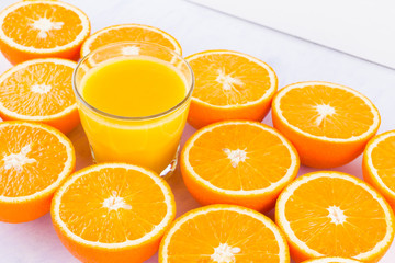 Halved oranges fruit and glass of juice. Citrus for making juice. A lot of sliced oranges on a white background. Background of oranges. Top view