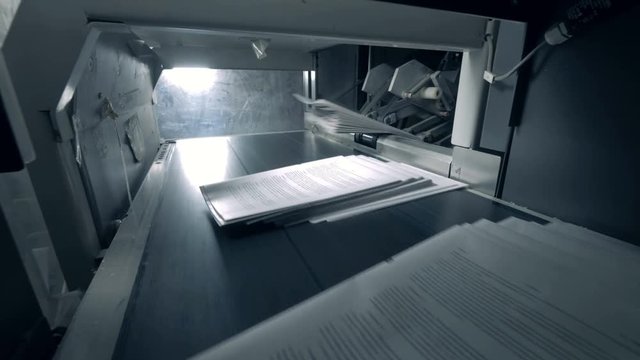 Piles of paper getting on automated conveyor, typography facility.