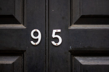 House number 95 with the ninety-five in silver on a black painted wooden door