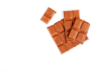 Milk chocolate pieces isolated on white background from top view