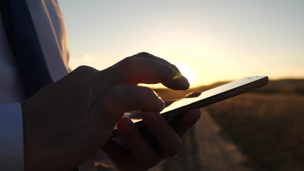 Businessman working on a tablet at sunset. hands of a man are driving their fingers over the...