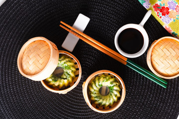 Asian Food concept homemade Dim Sum steamed garlic chives dumplings in Dim Sum Bamboo Steamer Basket on black matt background