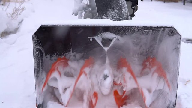 The spinning blades of the snowblower are milling much snow.