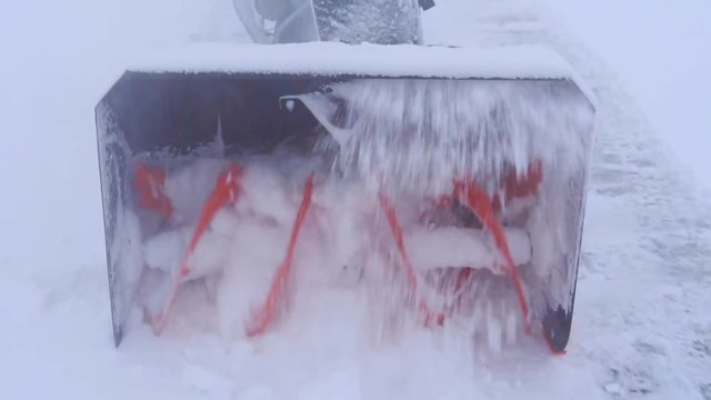 The spinning blades of the snowblower are milling much snow.