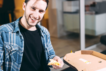 young man eating an appetizing pizza in the office