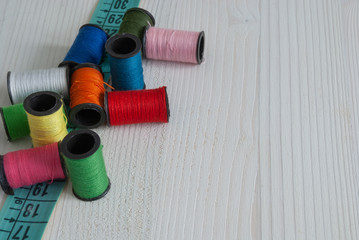 Top view of colored threads and tape measure. On white background with copy space