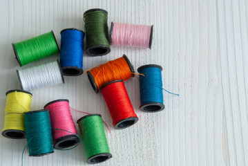 Top view of colorful threads on white wooden background and with copy space