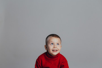 Portrait of an attractive laughing boy in a red sweater  close-up