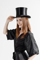 Fototapeta premium Studio-Porträt einer jungen Frau in schwarzem Kleid mit Chapeau Claque vor weißem Hintergrund