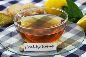 Healthy living card with cup of tea, fresh mint leaves, fresh ginger and juicy lemon, closeup