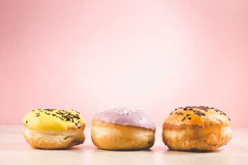 Donuts. Assorted donuts lying on a white table on pink background. Сoncept sweet food