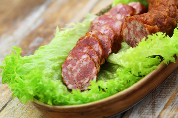 Slices of smoked pork sausage on lettuce leaves, closeup