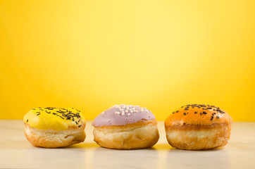 Donuts. Assorted donuts lying on a white table on yellow background. Сoncept sweet food