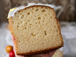 Half-cut homemade sweet easter bread in the hands of a baker's woman. Slice of easter orthodox sweet bread, kulich. Beautiful lace crumbs rolls. Close up, selective focus, copy space