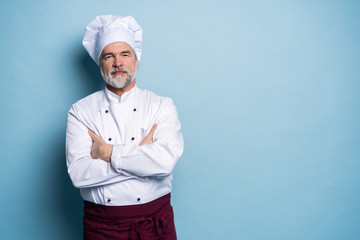 Attractive smiling cheerful chef isolated on blue.