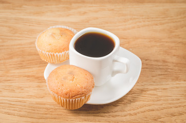 coffee break. White cup of the hot black coffee and two muffins. Breakfast concept