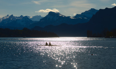 A lone skiff against the light before mountain range 