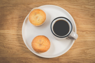 coffee break. Cup of the black coffee and cupcakes on a white tray, wooden table. Top view. Breakfast concept