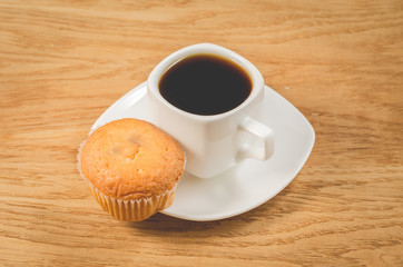 coffee break. White cup of the espresso and muffin on a wooden. Breakfast concept.