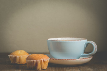 Coffee break. Muffins and mug with cappuccino for breakfast on a gray background