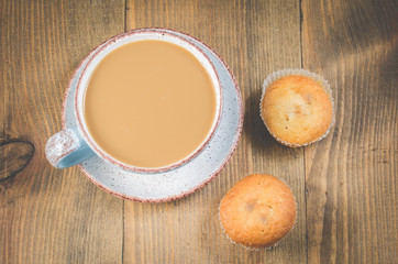 Coffee break. Muffins and mug with cappuccino for breakfast on a old wooden table. Top view