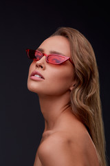 Portrait of beautiful young woman with perfect makeup wearing red sunglasses. Smiling fashion model...