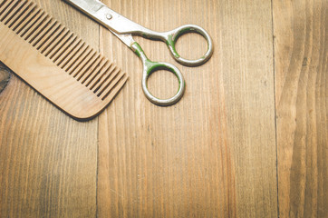 scissors and comb on old wooden background, top view and copy space. Barbershop concept