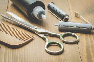 hairbrushes, sprayer, curlers and a scissors on a wooden board