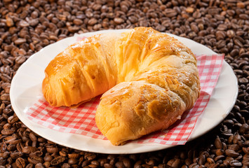 fresh croissant in coffee beans background - Top view