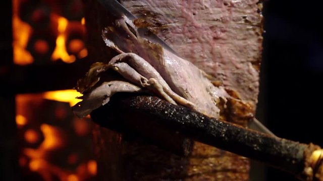 A cook cuts meat to make shawarma, gyros, doner kebab. Cooking meat on a skewer