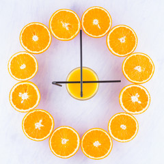 Fruit Dial. Creative idea of the clock from the halves of oranges fruit. Citrus watches, concept. Halved oranges on a white background. Top view