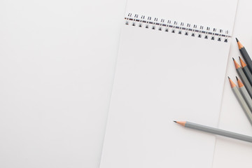 Top view, empty notebook with pencils on a white background.