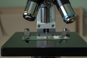 Microscope on the desk of the biologist with the micro-specimens, a scalpel and tweezers.