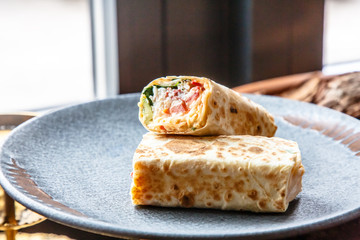 The Shawarma is wrapped in pita bread two piece lies on a plate