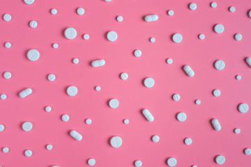 White pills on pink background.