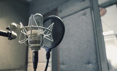 Studio microphone with shock mount and pop filter on professional tripod in acoustic foam room for...