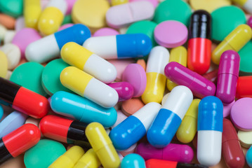 Medicine green, yellow, red and pink pills or capsules on a blue background