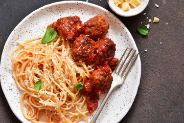 Spaghetti pasta with meatballs, tomato sauce and parmesan on the kitchen table. View from above.