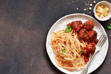 Spaghetti pasta with meatballs, tomato sauce and parmesan on the kitchen table. View from above.