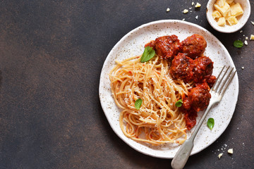 Spaghetti pasta with meatballs, tomato sauce and parmesan on the kitchen table. View from above.