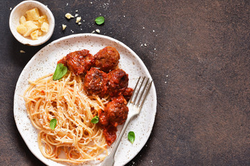 Spaghetti pasta with meatballs, tomato sauce and parmesan on the kitchen table. View from above.