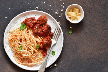 Spaghetti pasta with meatballs, tomato sauce and parmesan on the kitchen table. View from above.