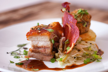 Pork Belly served with crispy bacon in a fine dining restaurant on a white plate
