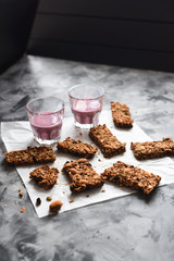 Healthy sugar free gluten free vegan snack. Blueberry smoothie and oatmeal chocolate granola bars with almonds and amaranth seeds on baking paper